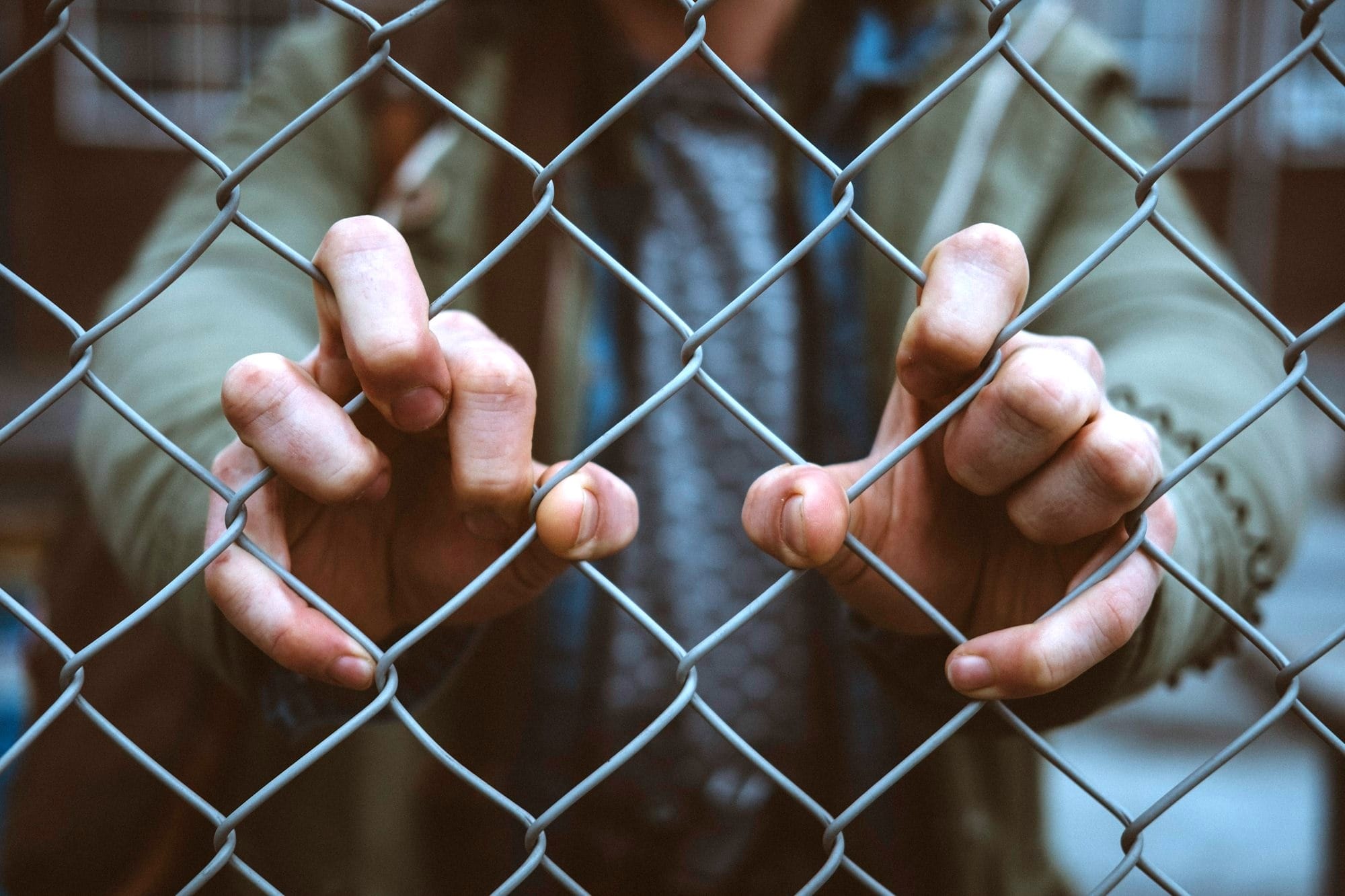 person behind mesh fence